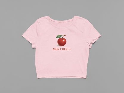 Pink t-shirt with a red apple graphic and 'MON CHERIE' text on a gray background