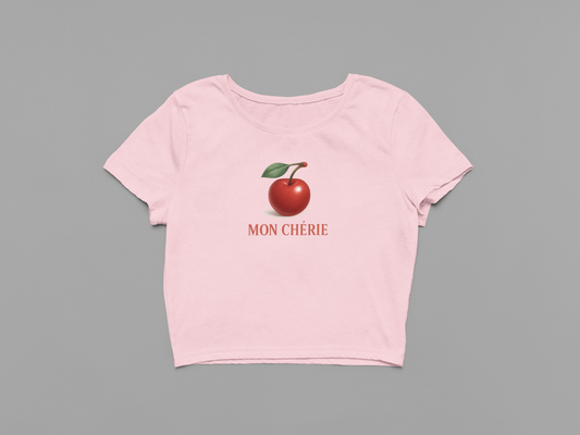 Pink t-shirt with a red apple graphic and 'MON CHERIE' text on a gray background